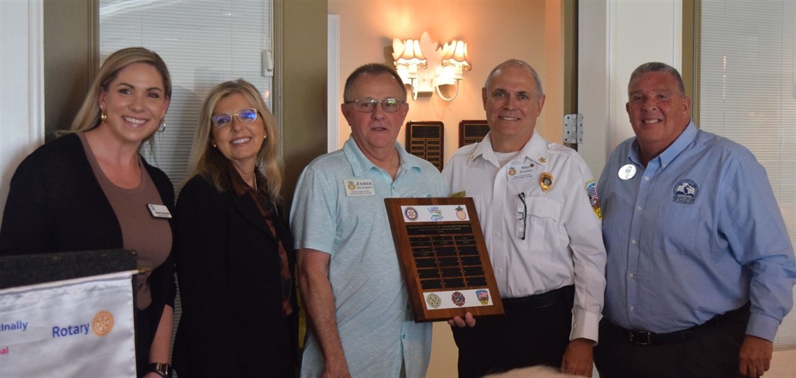 Kelsey Gonzalez and Ruthie Haffner of Lake Cares, retired Lake County Fire Chief James Dickerson, Chief Swanson and Eustis Mayor Michael Holland with Tri-City Challenge Award