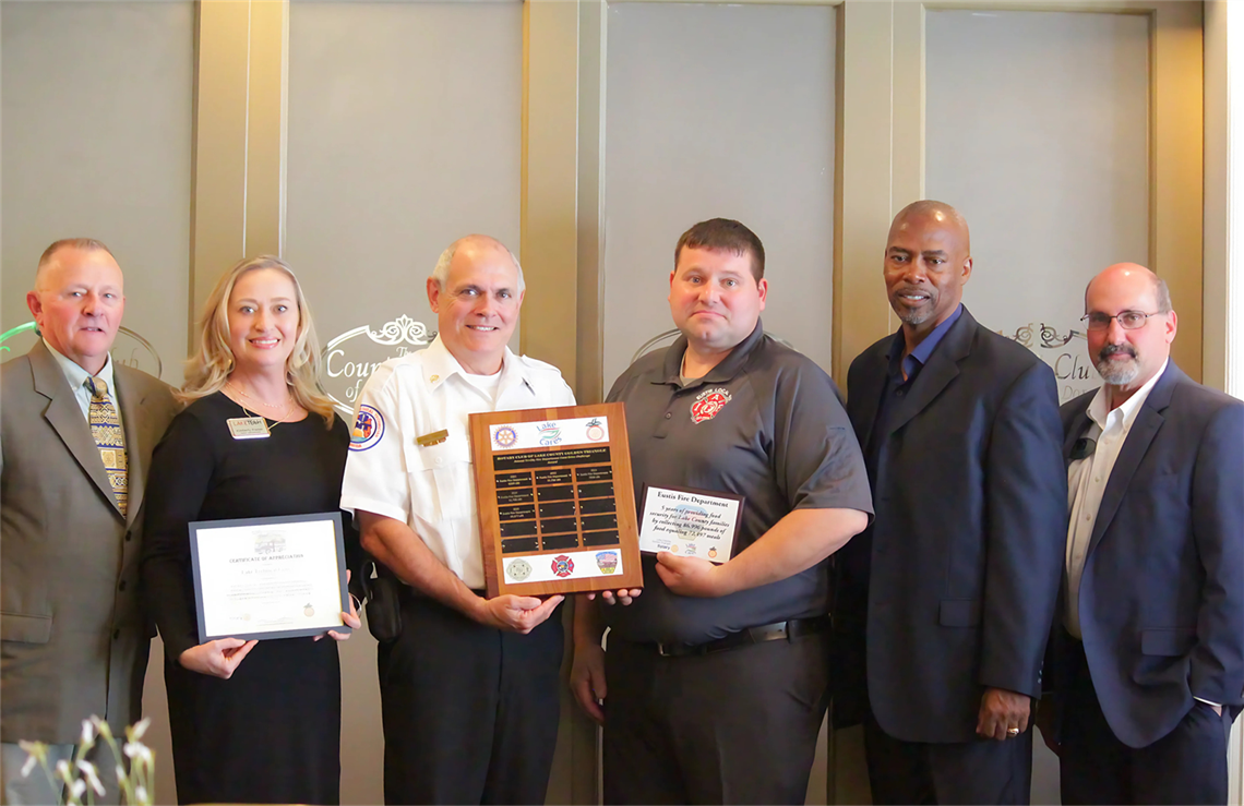 Eustis Fire Chief Mike Swanson, Mayor Willie Hawkins and City Manager Tom Carrino accepting Food Drive Challenge plaque.