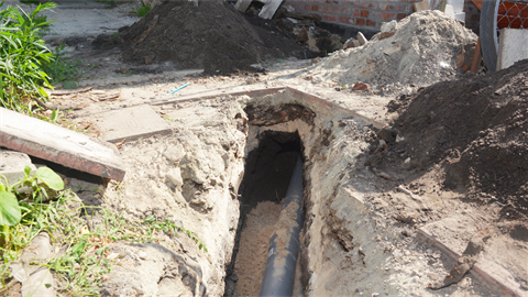 Sewer line exposed being repaired in ground during construction